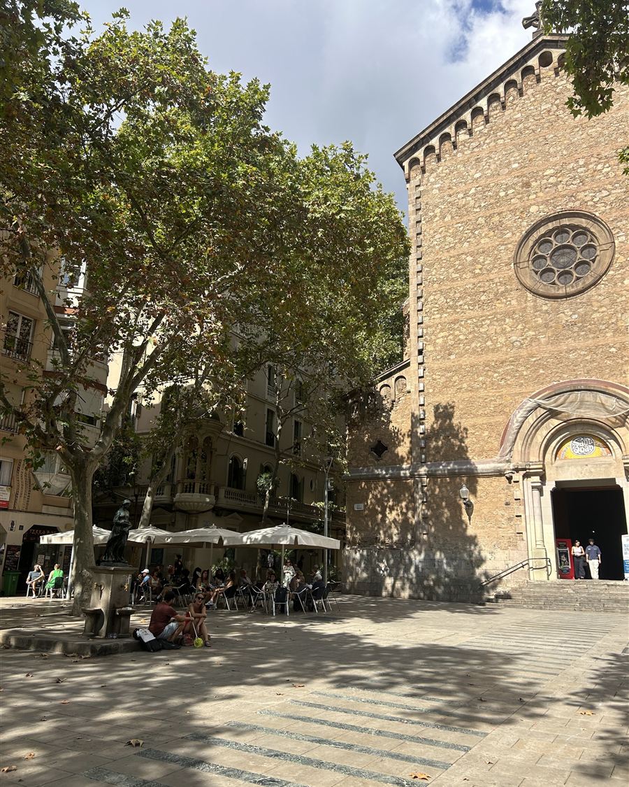A shaded plaza in front of a stone church in Barcelona